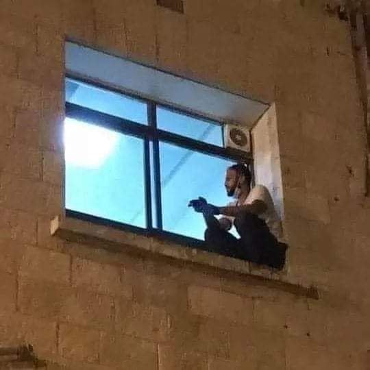 كان يتسلق جدار المشفى لمراقبتها.. صور مؤثرة لشاب فلسطيني ظل يتابع والدته المصابة بكورونا حتى ماتت