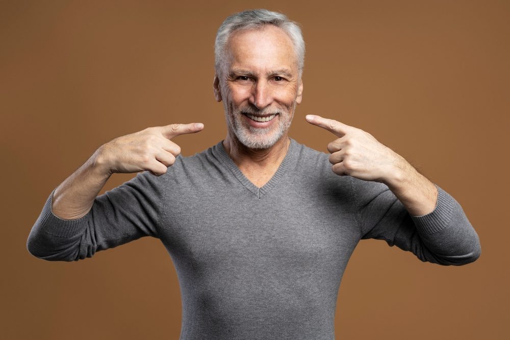 رجل سعيد باستعادته الأسنان التي فقدها